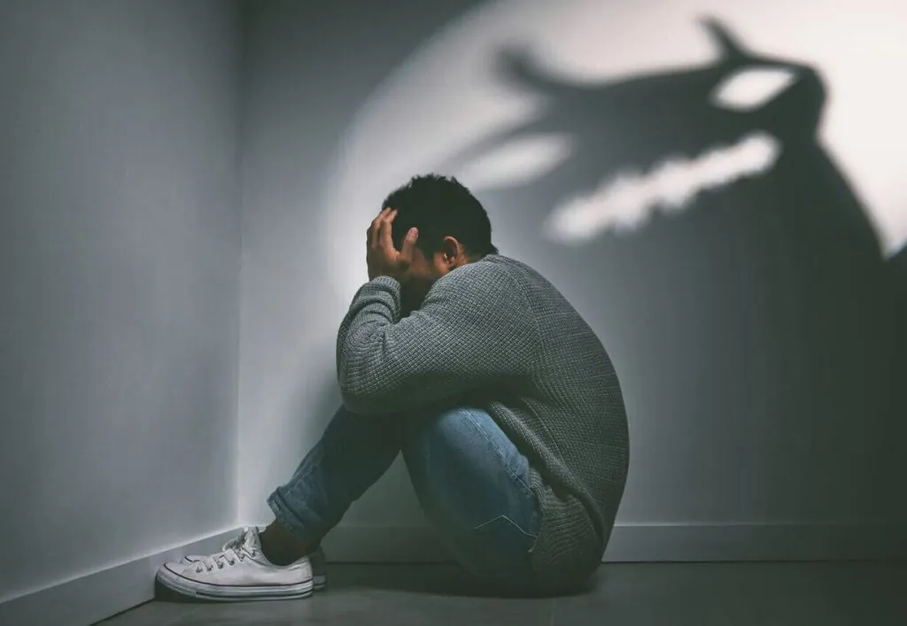 Man Sitting In Corner Of Dark Room